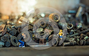 Male photographer standing to take photo a female model on pile of old screws nuts and bolts