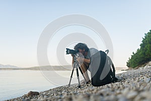 Male photographer taking photos on a pebble beach