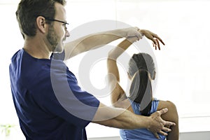 Male Physical Therapist Stretching a Female Patient Slowly.