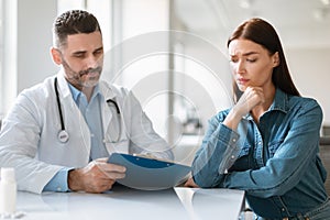 Male physician discussing check up results with woman during meeting at hospital, doctor explaining details of treatment