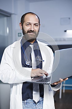 Male physician holding a digital laptop