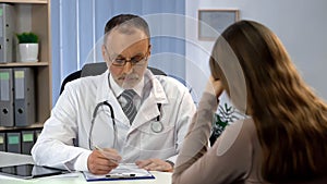 Male physician informing patient about high cost of surgery, woman in despair photo