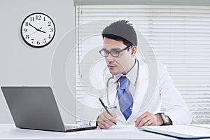 Male physician with notebook in office