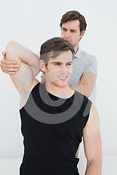 Male physiotherapist stretching a smiling young mans arm