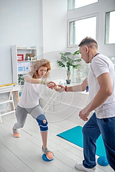 Male physiotherapist supporting female patient with lunging