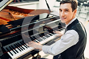 Male pianist poses at the black grand piano