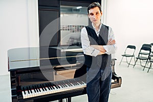 Male pianist stands at the black grand piano