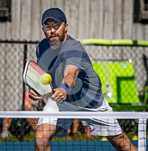 Male pickelball player reaches for the ball during a tournament