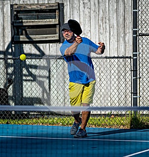 Male pickleball player hits the ball from the baseline