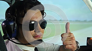 Male pilot enjoying his work, sitting in cockpit of airliner, showing thumbs up