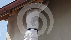 Male plasterer builder plastering the facade of the building standing on scaffolding, repairing the facade of the