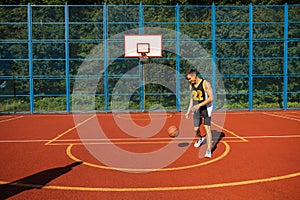 Male playing basketball alone outdoor at court.