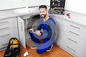 Male plumber with clipboard near kitchen sink