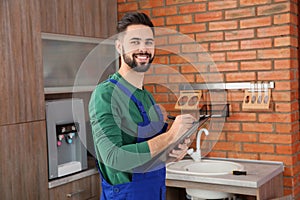Male plumber with clipboard near kitchen sink
