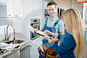 Male plumber and female customer in the kitchen