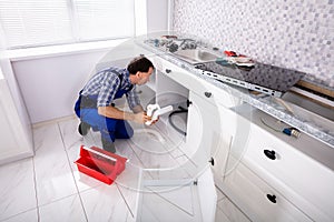 Male Plumber Fixes Sink Siphon In Kitchen