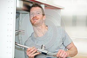 male plumber fixing sink pipe at home