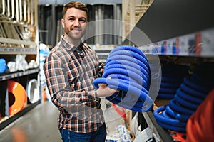 male plumber in a hardware store chooses the sewer pipes, the concept of plumbing work in the house