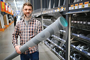 male plumber in a hardware store chooses the sewer pipes, the concept of plumbing work in the house