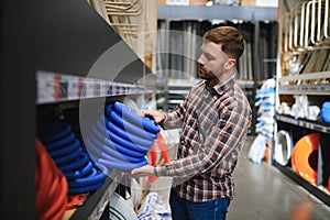 male plumber in a hardware store chooses the sewer pipes, the concept of plumbing work in the house