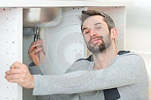 Male plumber installing kitchen sink using wrench