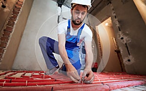 Male plumber installing underfloor heating pipes.