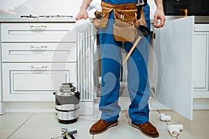 Male plumber installing water filter in kitchen