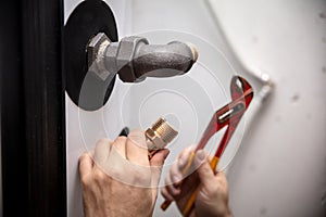 male plumber with pipe wrench installs a new pellet heater in the basement