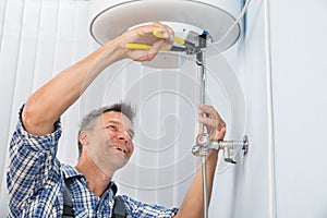 Male plumber repairing electric boiler