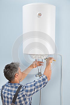 Male plumber repairing electric boiler photo