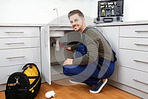 Male plumber repairing kitchen sink