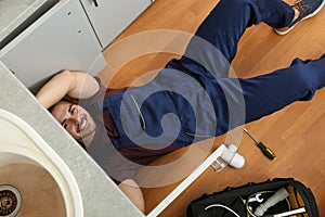 Male plumber repairing kitchen sink