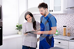 Male Plumber Showing Invoice To Woman