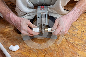 Male plumber solders polypropylene plastic pipes with an electric apparatus for welding pipes