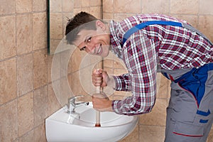 Male Plumber Using Plunger In Sink