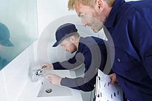 male plumber working on sink using wrench