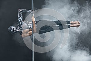 Male pole dancer posing in dark studio