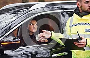 Male police officer in green uniform taking bribe from vehile driver on the road