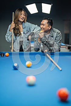 male pool player holding the yellow ball while smiling