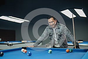 male pool player smiling while put his hands on the pool