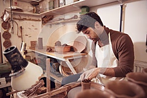 Male Potter Shaping Clay For Pot On Pottery Wheel In Ceramics Studio