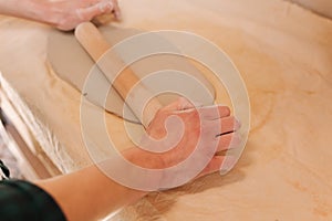 Male potter use rollong pin for clay. Man in workshop