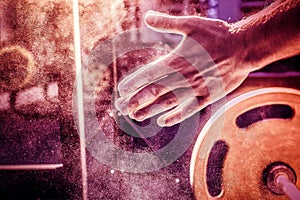 Male powerlifter hand in talc. preparation before lifting weights. Toned image.