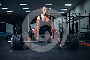 Male powerlifter preparing deadlift barbell in gym