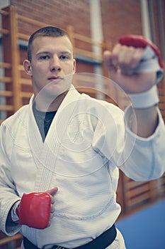 Male practicing judo in kimono with fight glove.