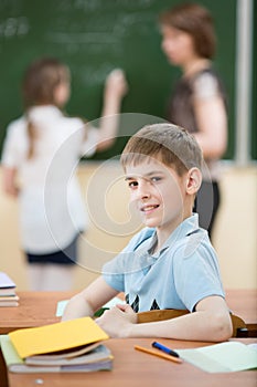 Male primary school student in classroom with classmate and teacher