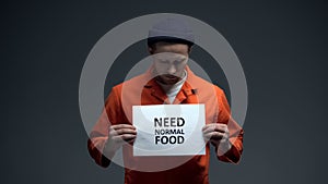 Male prisoner holding Need normal food sign, ill treatment in jail, starving