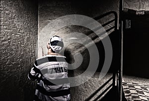 Male prisoner is sitting in the corner and praying in a small pr