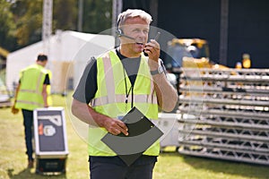 Male Production Worker With Headset Setting Up Outdoor Stage For Music Festival Or Concert