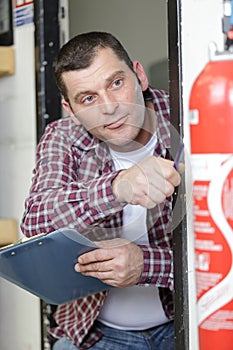 male professional checking fire extinguisher using clipboard